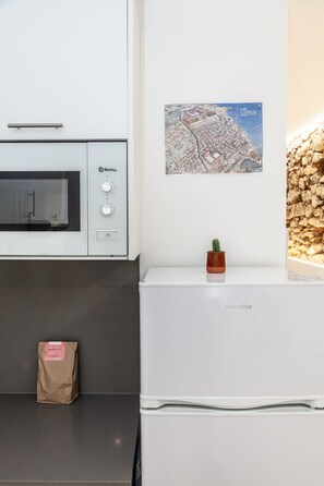 A kitchenette with a built-in oven, a small potted plant, and a welcome pack on the counter. - Old Town • Studio - Unik Vacation (Tarragona)