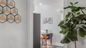 A hallway with a geometric wall art, a bicycle artwork, and a potted plant. - Heart of Fountain Inn: 2BR Gem (Fountain Inn)
