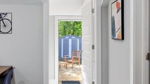 A hallway leading to a backyard with a blue shed and a wooden chair. - Heart of Fountain Inn: 2BR Gem (Fountain Inn)