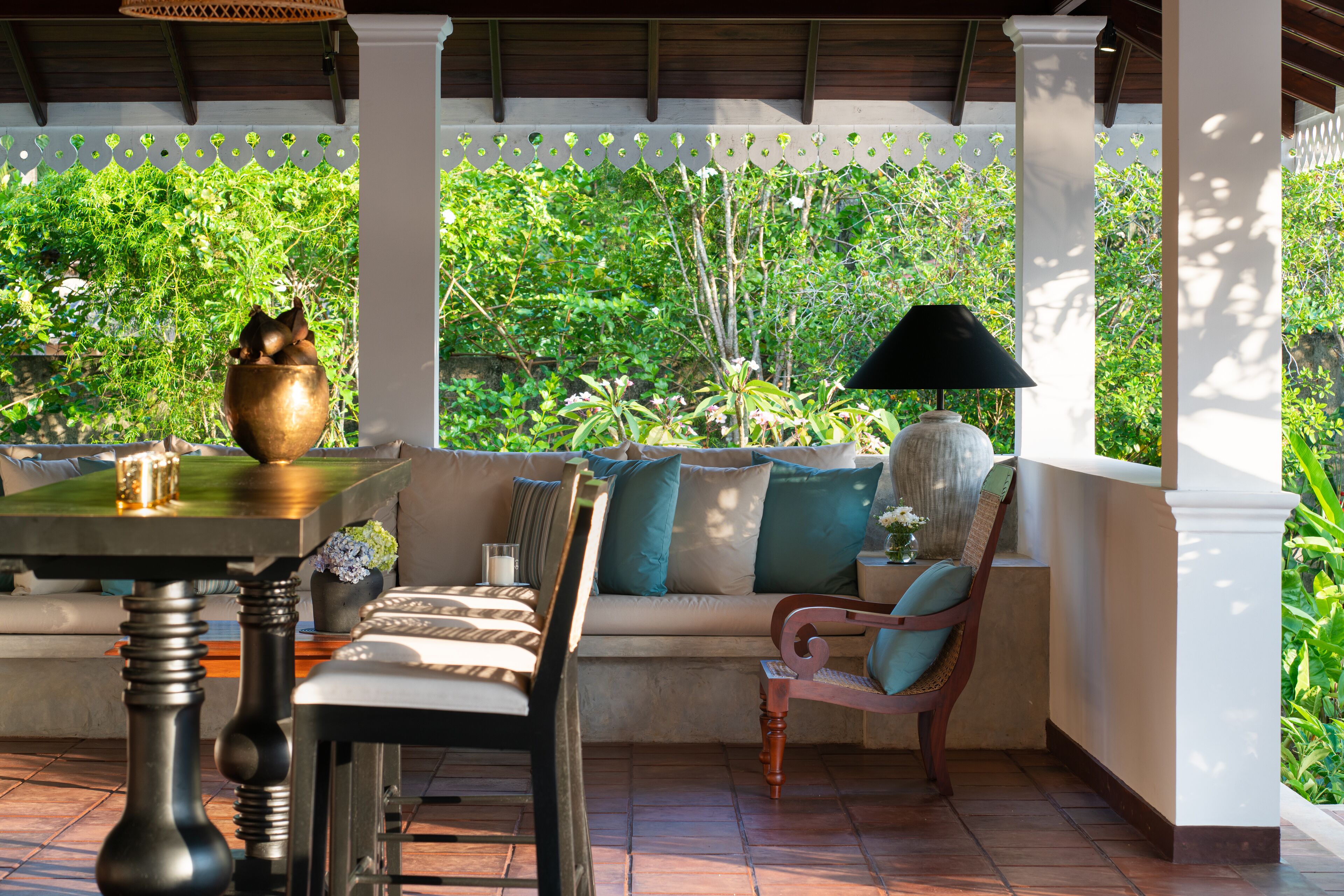 A covered outdoor seating area with a sofa, chairs, a table, and a decorative bowl.