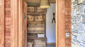 Eine Holztreppe mit einer gewobenen Leuchte, einer Steinwand und einem Paar Ski, die an der Wand hängen.