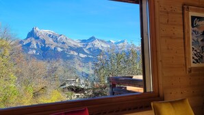 Blick auf Berge von einer Holzhütte mit einer Holzdar Terrasse und einem gerahmten Bild an der Wand.