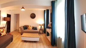 A living room with a sofa, a coffee table, a TV, and a painting of a bridge. - Appartement Chez Kate & Jack à 5 Minutes à Pied de la Cathédrale Saint Just (Narbonne)