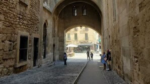 A narrow cobblestone street with an arched passageway, stone buildings, and a few people walking. - Appartement Chez Kate & Jack à 5 Minutes à Pied de la Cathédrale Saint Just (Narbonne)