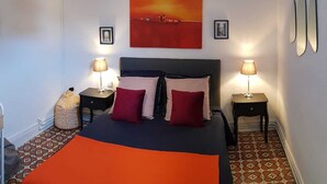 A bedroom with a bed, two bedside tables, two lamps, a hanging light, and a painting on the wall. - Appartement Chez Kate & Jack à 5 Minutes à Pied de la Cathédrale Saint Just (Narbonne)