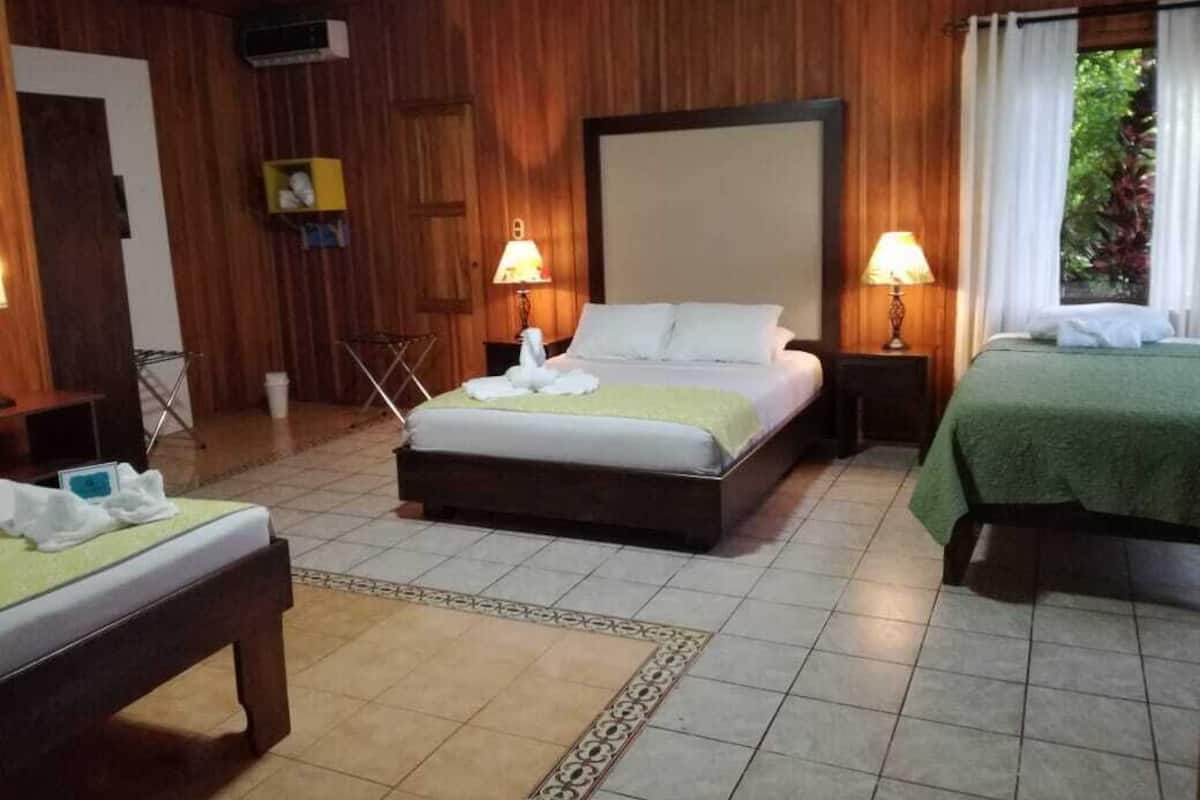 A hotel room with two beds, a wooden wall panel, a tiled floor, and two bedside lamps.