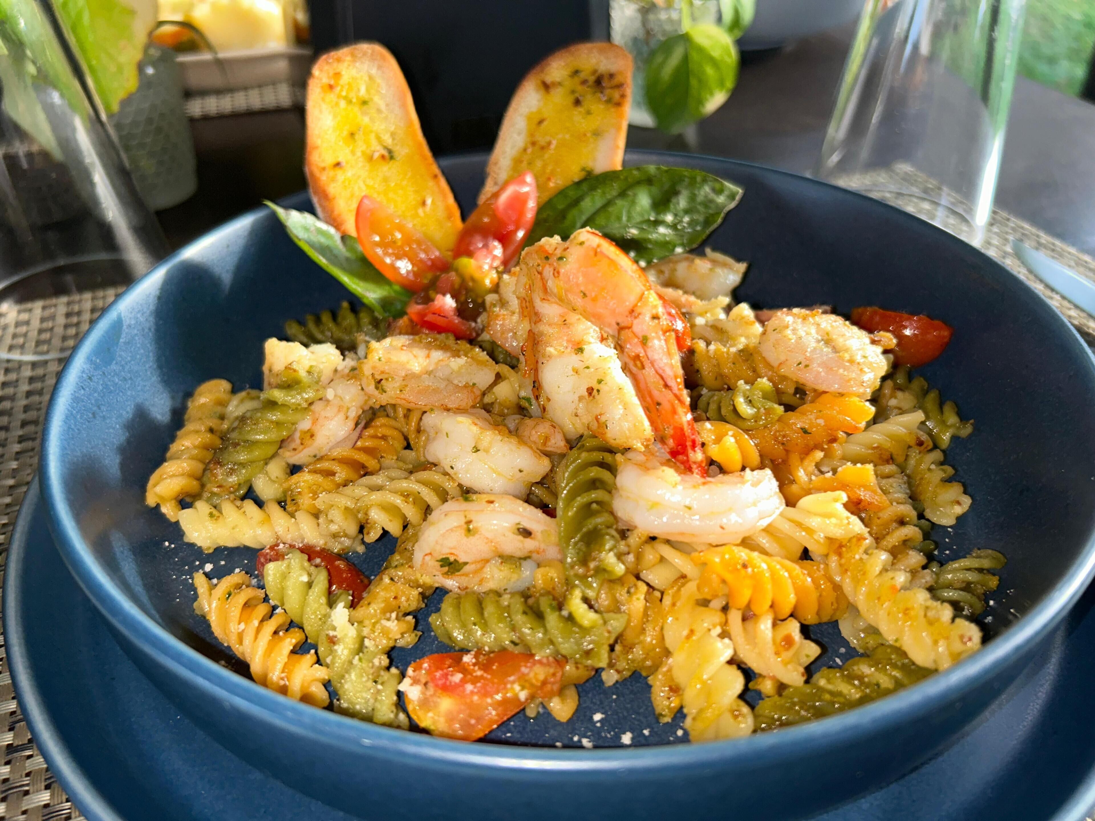 A bowl of pasta with shrimp and vegetables.