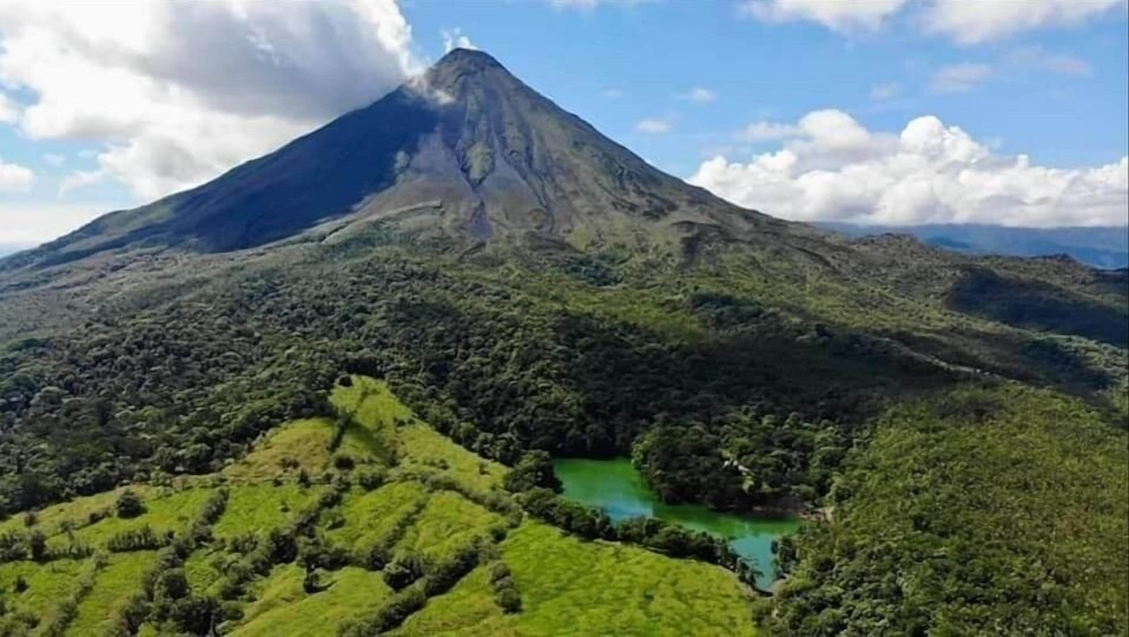 A mountain with a green valley and a clear blue lake.