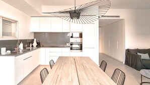 Cozinha moderna com armários brancos, mesa de jantar de madeira e uma luminária pendente exclusiva.