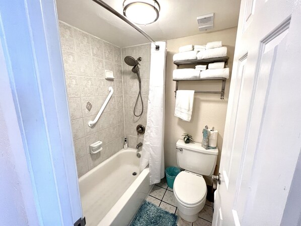 A bathroom with a bathtub, toilet, shower, and a towel rack.