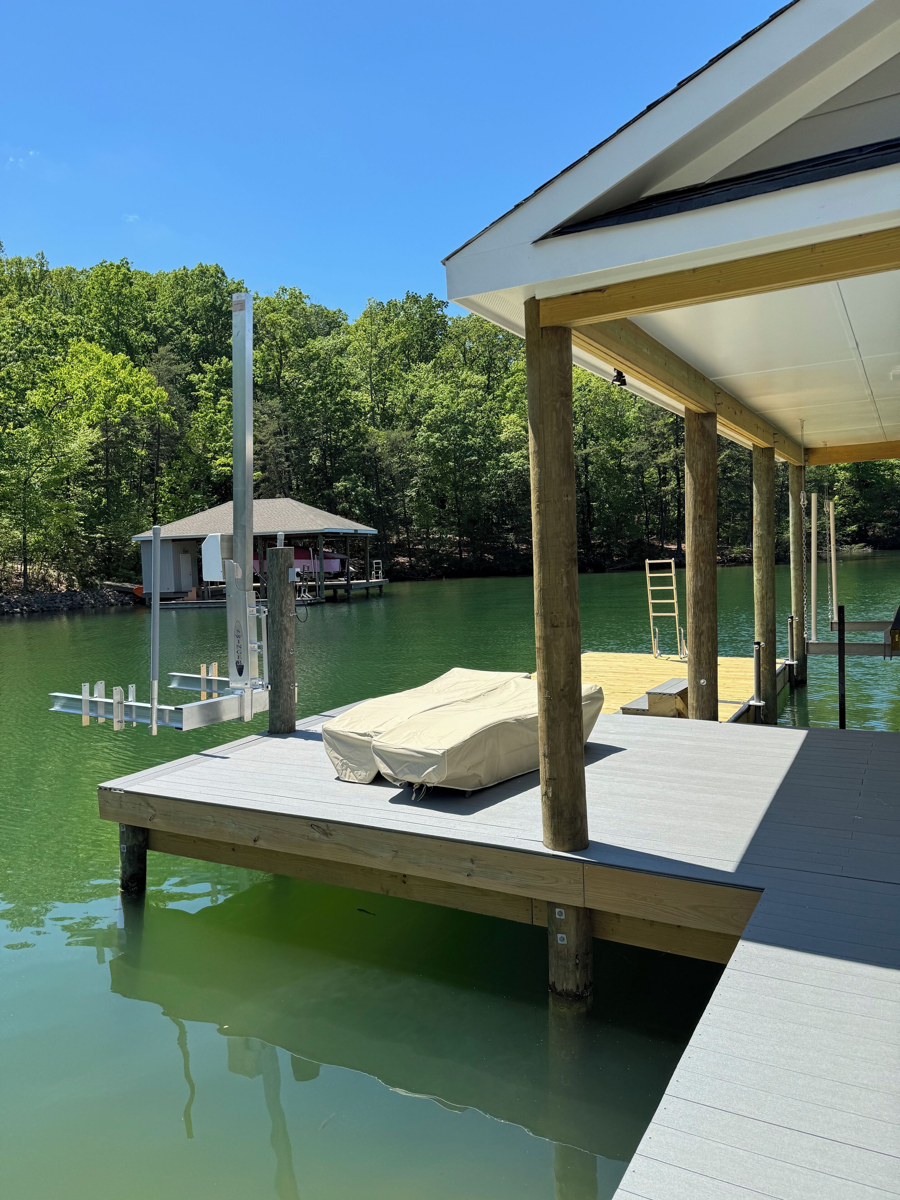 A dock extending into a body of water with a covered seating area and a small structure in the background.