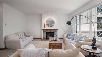 A modern living room with a fireplace, two sofas, a coffee table, and a large window.