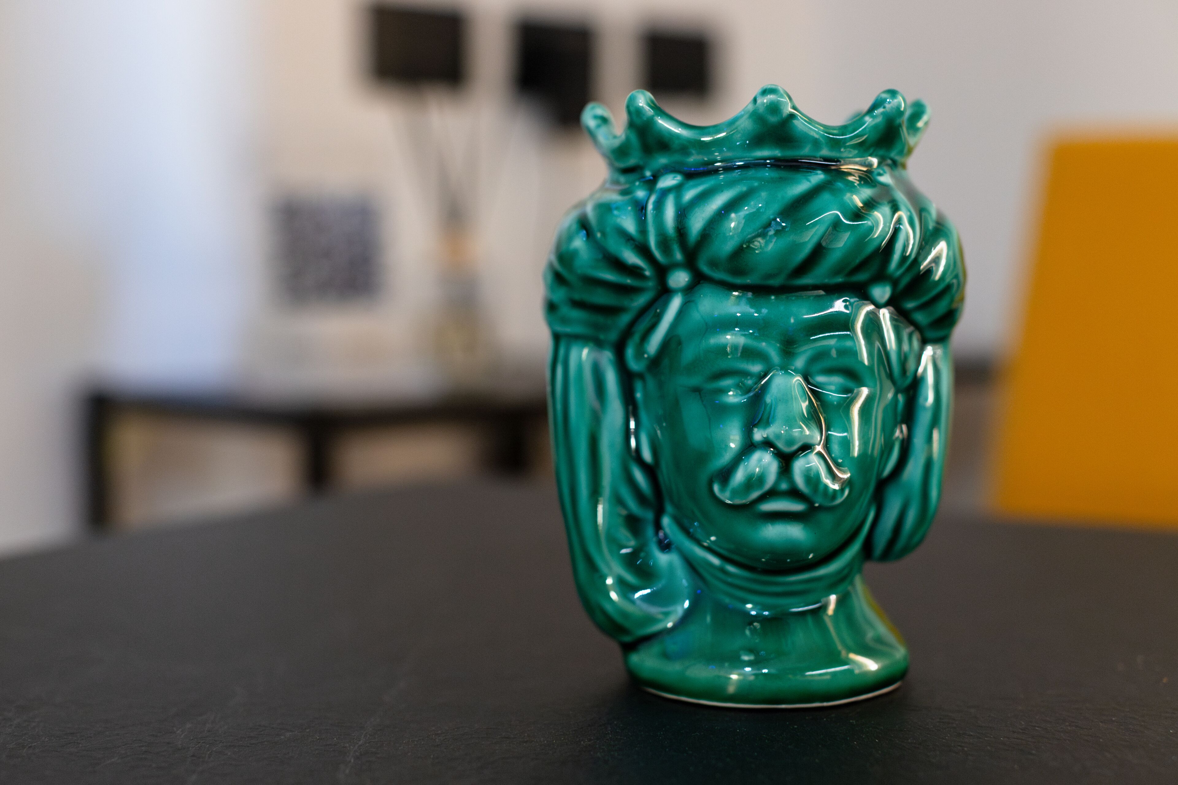 En grøn keramisk figur på et sort bord.