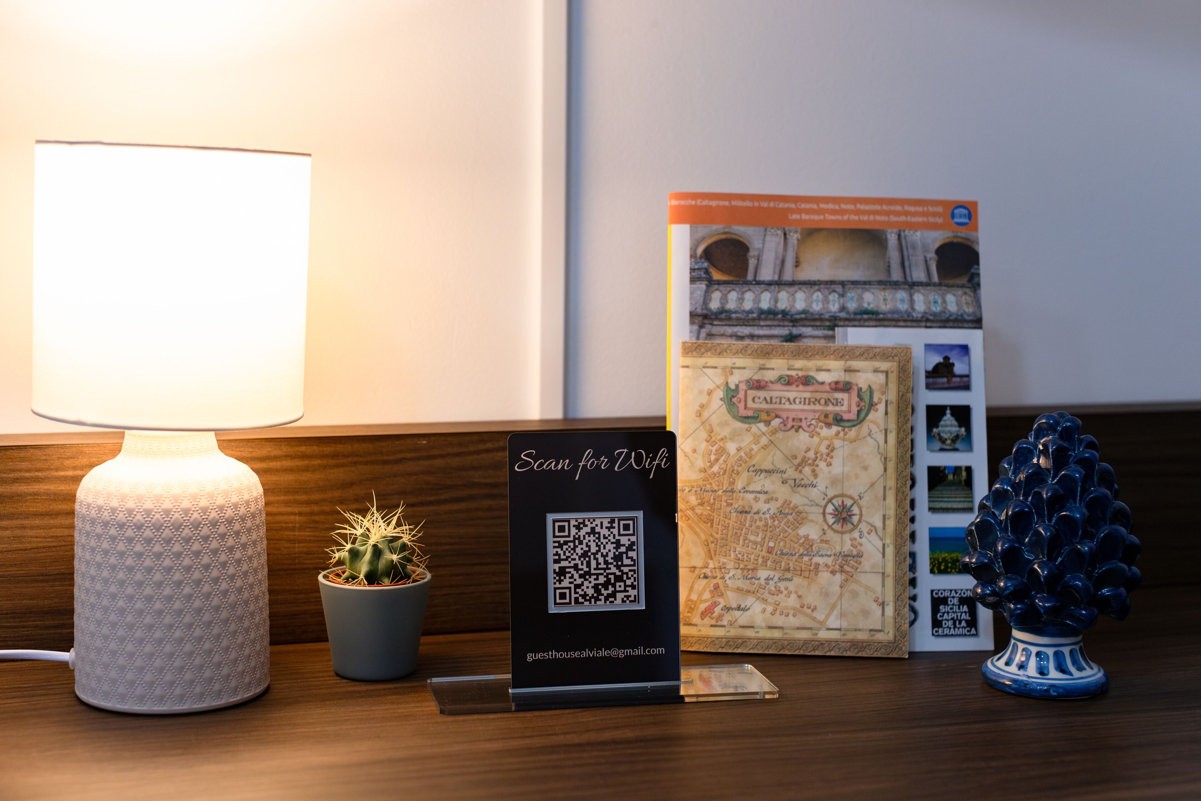A table with a lamp, a QR code sign, a small potted plant, a decorative ceramic tree, and a map.
