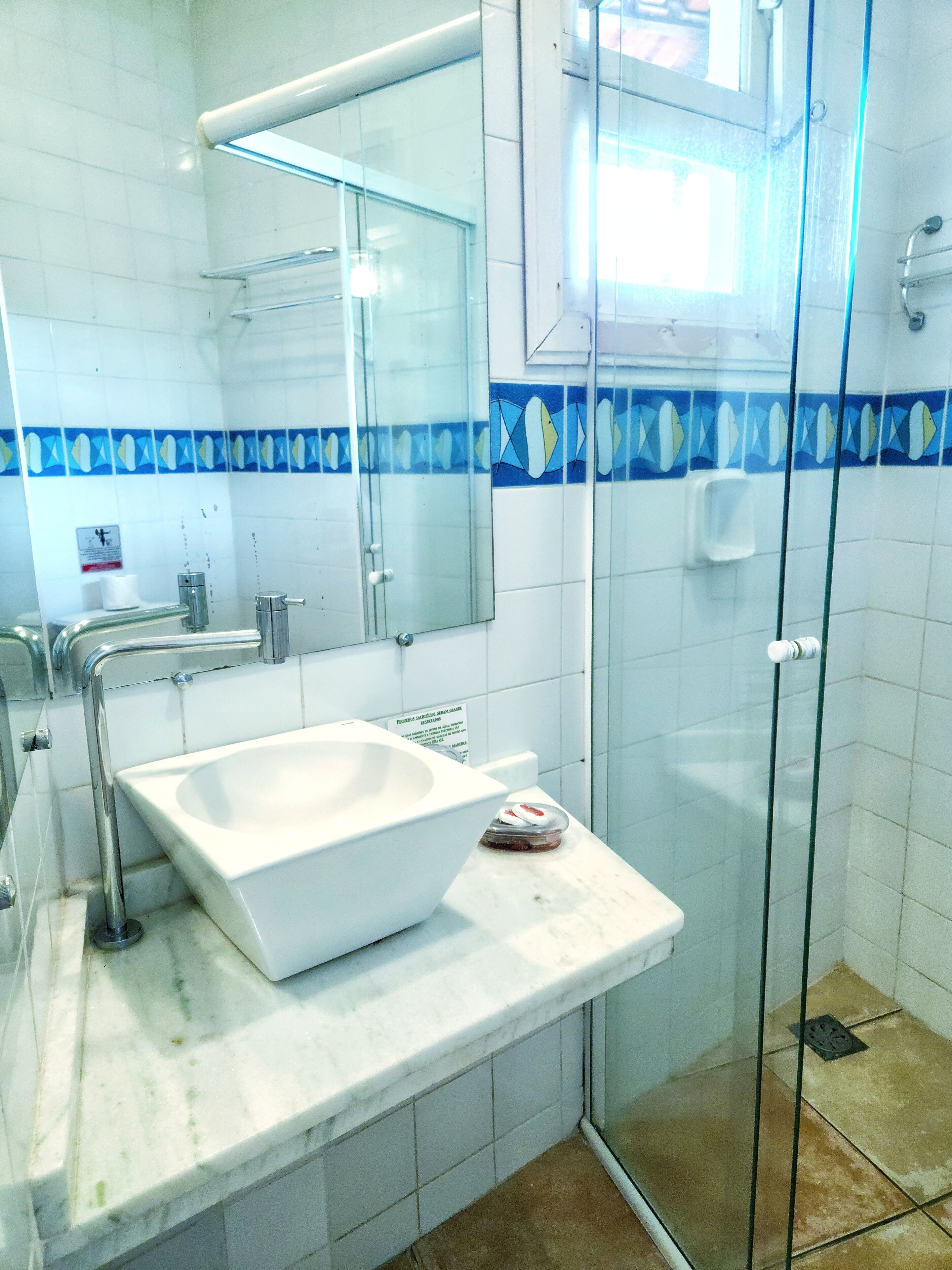 A bathroom with a white sink, a glass shower enclosure, and blue decorative tiles.