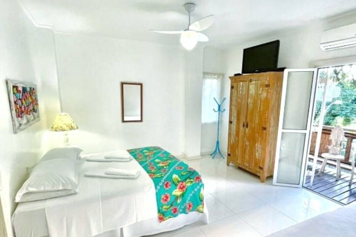 A hotel room with a bed, a desk, a chair, a wardrobe, and a window.