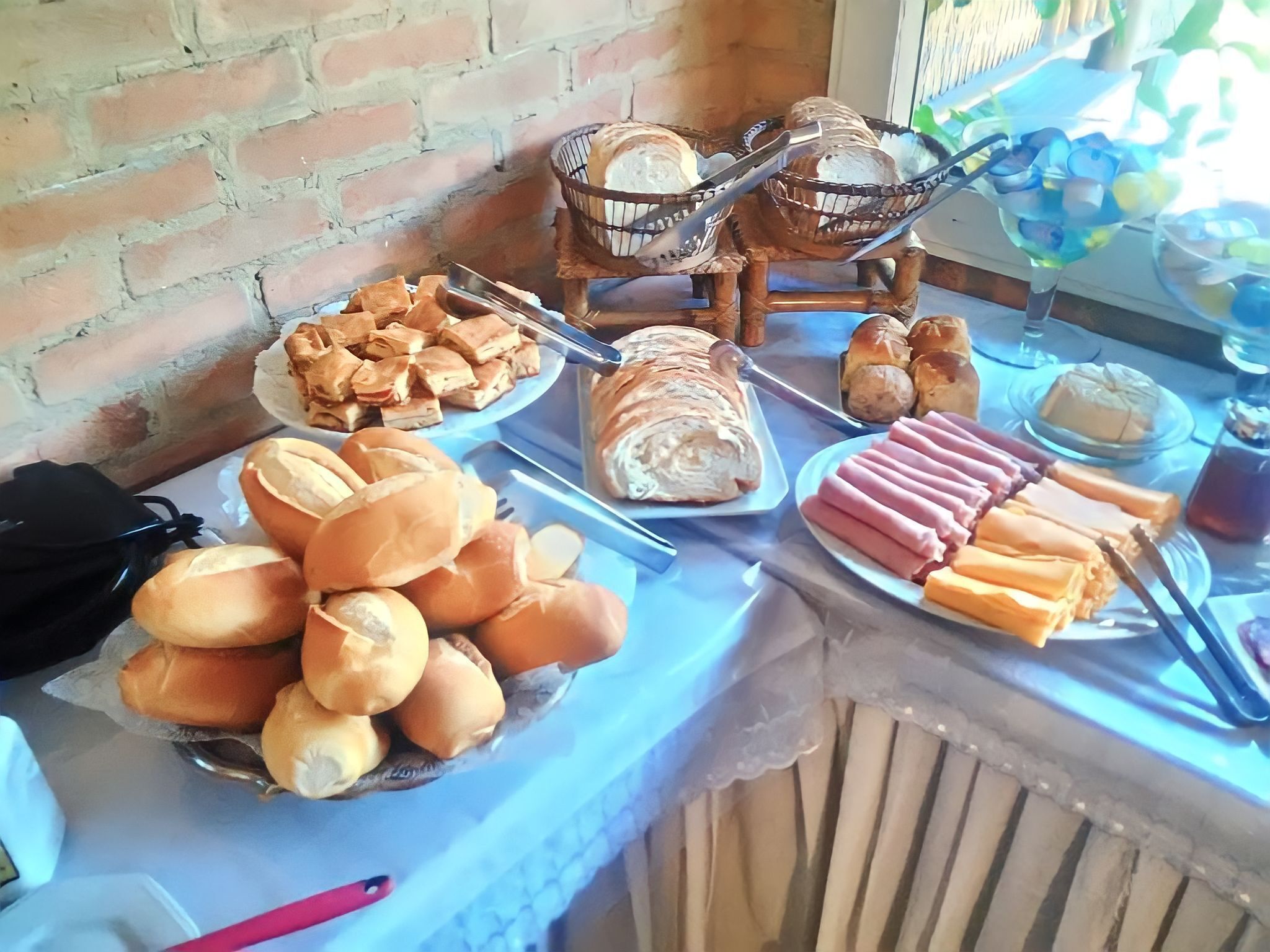 Een buffet met diverse gerechten, waaronder brood, gebak en vleeswaren.