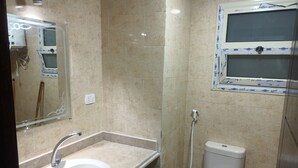 Un baño con lavamanos, espejo, inodoro y ducha.