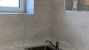 A kitchen with a stainless steel sink, white cabinets, a window, and a bottle of hand soap on the countertop. - Foria House Naples (Napoli)