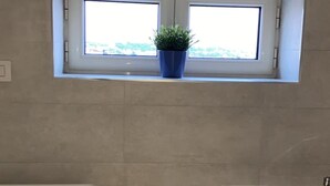 A compact kitchen with a window, a sink, and a small cabinet. - Foria House Naples (Napoli)