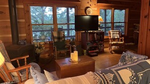 A cozy cabin interior with a fireplace, a television, and a bookshelf.