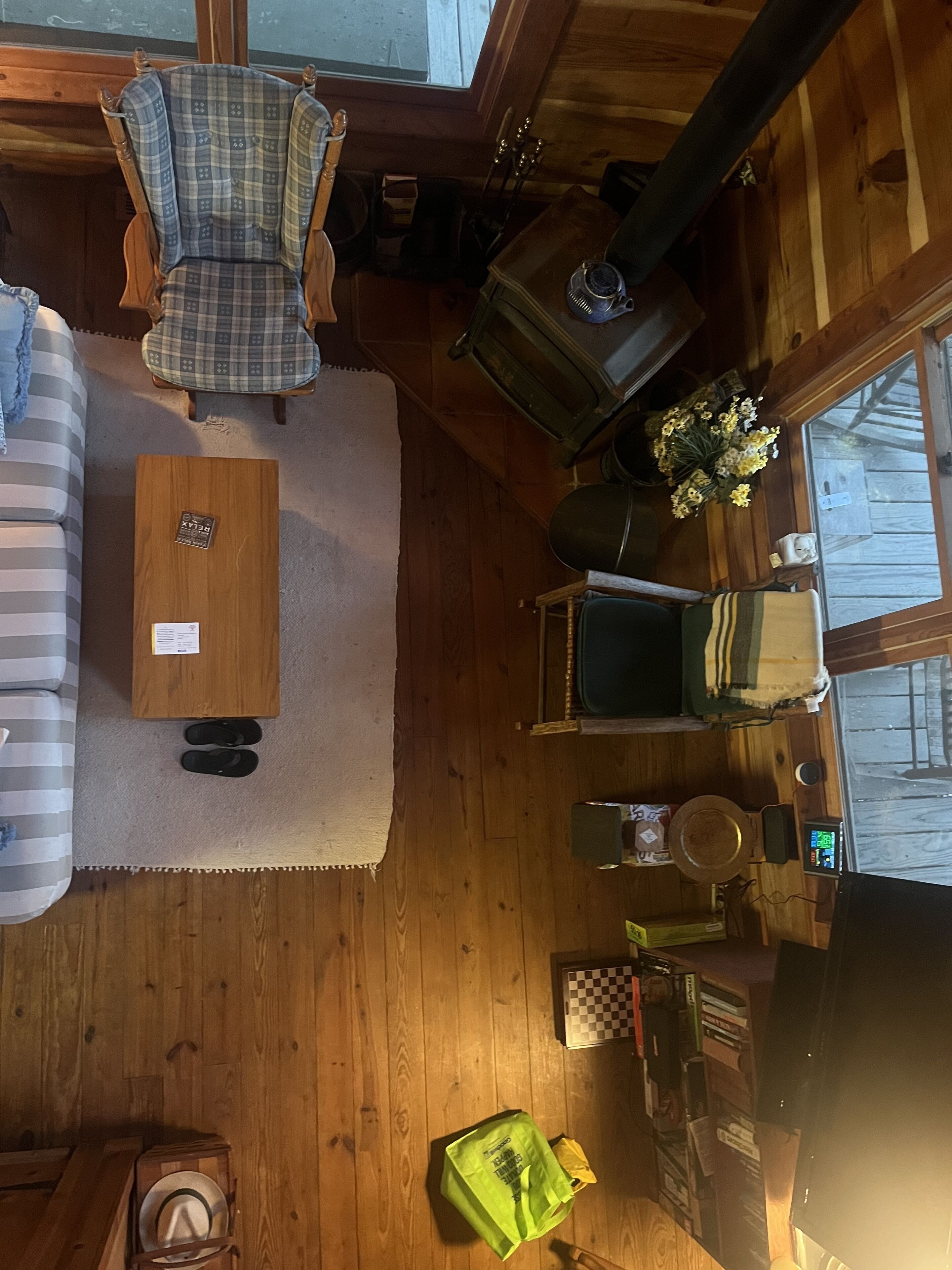L’intérieur d’un chalet accueillant, avec un fauteuil à carreaux, un canapé rayé, une table basse en bois, une cheminée et une bibliothèque.