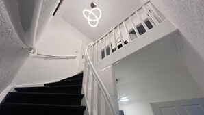 Escada com corrimão branco e luminária moderna acima.