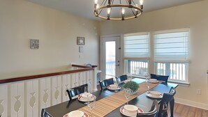A dining area with a long table, chairs, and a chandelier. - Unobstructed Ocean View, 4BR Beach House, Sleeps 12, Pet Friendly. (Surfside Beach)