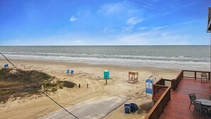A beach view with a wooden deck, beach chairs, and a lifeguard stand. - Unobstructed Ocean View, 4BR Beach House, Sleeps 12, Pet Friendly. (Surfside Beach)