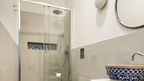 Une salle de bain moderne dotée d’une douche à parois de verre, de toilettes, d’un bidet et d’un lavabo agrémenté d’un récipient décoratif.