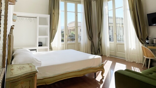 Une chambre d’hôtel avec un grand lit, un bureau, une chaise et un téléviseur.