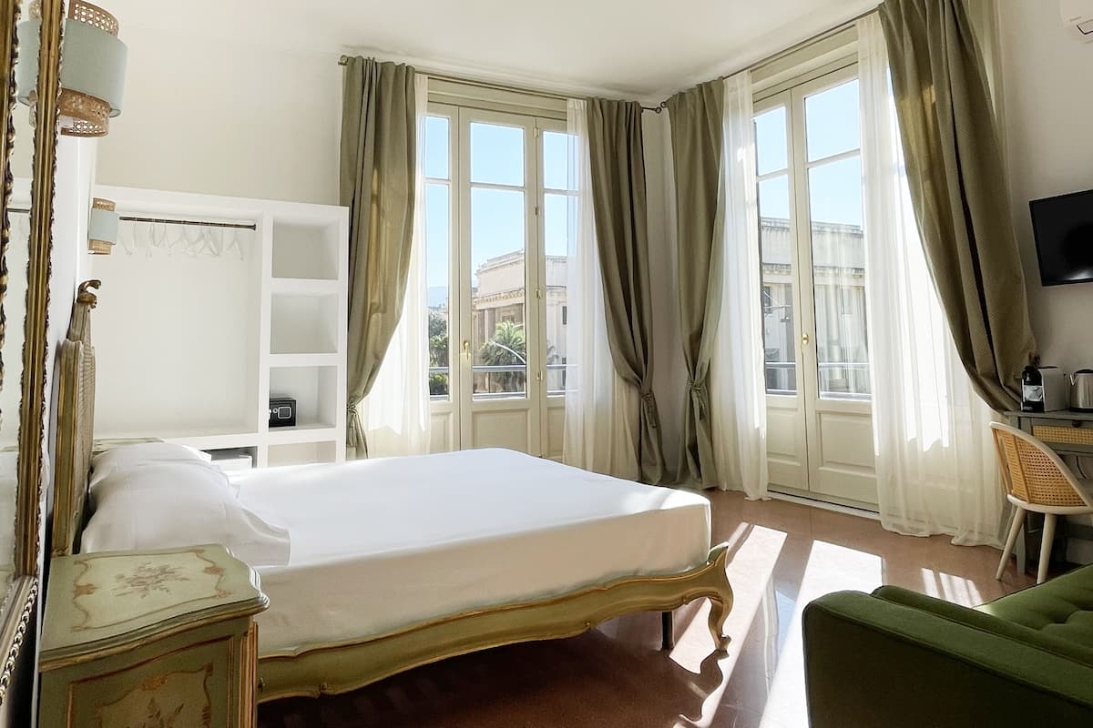 A hotel room with a large bed, a desk, a chair, and a TV.