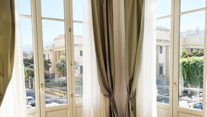Une chambre d’hôtel avec de grandes fenêtres, un lit et une vue sur le paysage urbain.