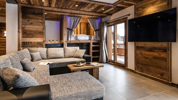 Ein modernes Wohnzimmer mit einem Ecksofa, einem flachbildfernseher an der Wand und Holzvertäfelung an Wänden und Decke.