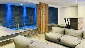 Ein moderner Wellnessbereich mit Whirlpool, Sitzgelegenheiten und einer Holzwand.