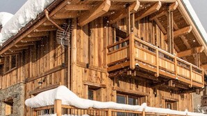 Ein Holzhaus mit Balkon und Whirlpool davor.