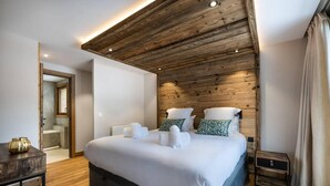 Ein modernes Schlafzimmer mit Holzboden, einem großen Bett mit weißer Bettwäsche und einem kleinen Nachttisch.