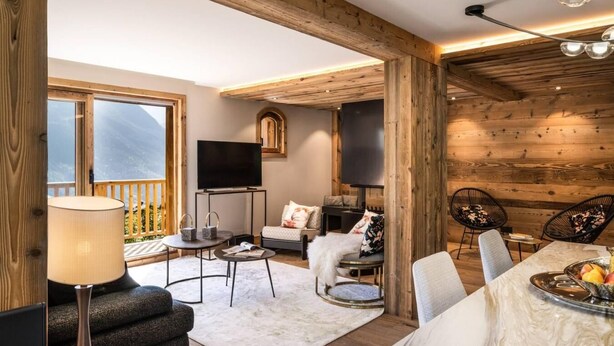 Ein gemütliches Wohnzimmer mit Kamin, Fernseher und Essbereich mit Tisch für zwei Personen.