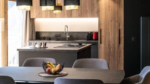 Uma cozinha moderna com ilha central, armários de madeira e luminárias pendentes.
