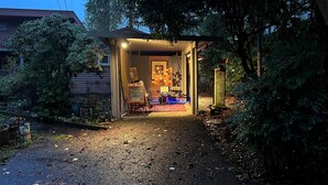 Una construcción pequeña y tenuemente iluminada, con una puerta de madera, un cartel de pizarra y algunas sillas y mesas en su interior.