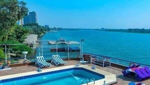 A pool area with lounge chairs and a view of the water. - River Nile Boat (Cairo)