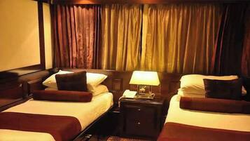 A hotel room with two beds, each with a pillow and a bedside table with a lamp.