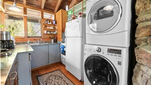 A compact kitchen with a washing machine, a refrigerator, and a sink. - Clerestory Cottage (Big Bear Lake)