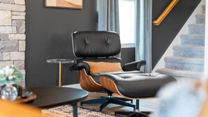 A modern living room with a leather armchair, a small round table, and a staircase in the background.