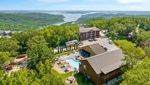 A lodge with a pool, surrounded by lush greenery and a view of a river.