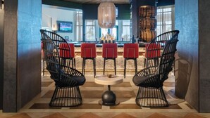 Un'area bar moderna con sedie in metallo nero, un tavolo rotondo e un soffitto in legno.