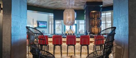 Un área de bar moderna con sillas de estructura metálica negra, una mesa redonda y un techo de madera.