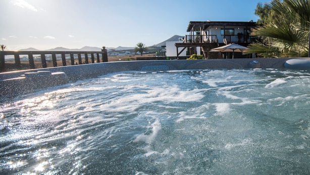 A hot tub area with a view of a building and mountains in the background.