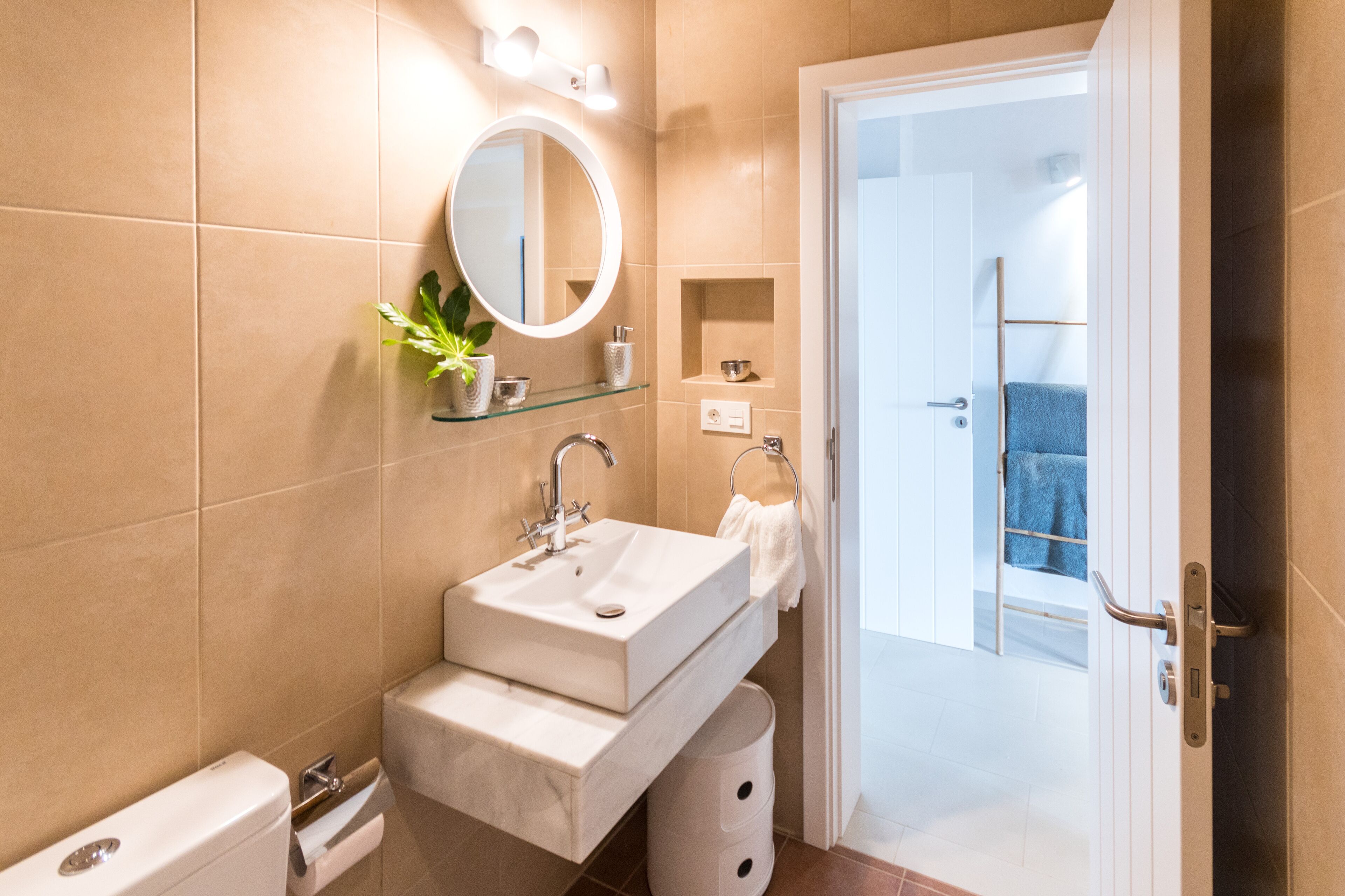 Een moderne badkamer met een wastafel met twee kommen, een spiegel, een handdoekhouder en een klein plankje met toiletartikelen.