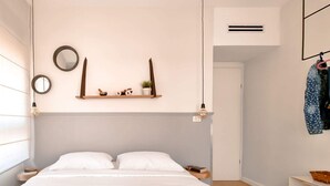 A bedroom with a bed, bedside tables, a wall-mounted shelf with decorative items, and a hanging light fixture. - Ness Tsiyona Cachemire (Tel Aviv)
